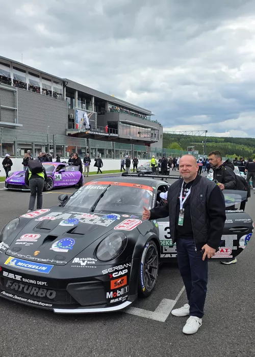 Porsche 911 Cup von Proton Competition in der Startaufstellung vor dem Rennen im Porsche Carrera Cup Deutschland. secura protect Mitarbeiter Rajko Matek im Vordergrund und zeigt Daumen hoch in Spa-Francorchamps