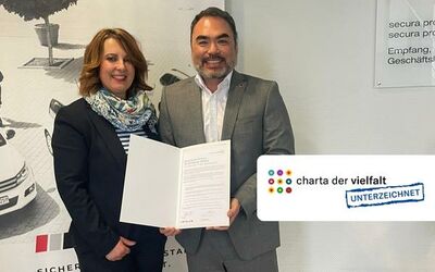 Pratrick Pond und Tanja Pond von secura protect halten Urkunde der Charta der Vielfalt